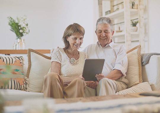 Elderly couple using tablet on couch